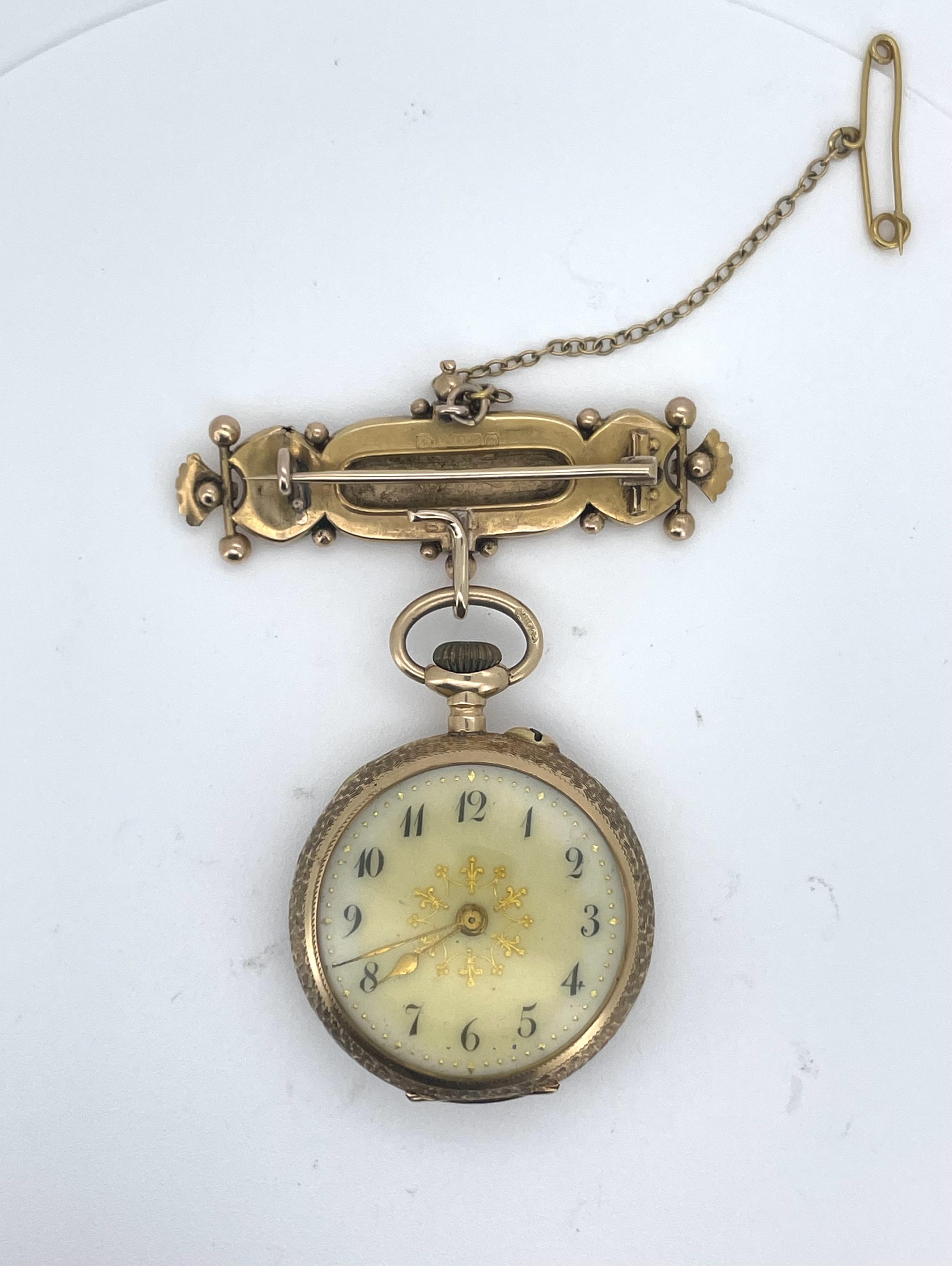 A lady's gold and Swiss enamel fob watch, circa 1907, the cream dial with gold enamel decoration and Arabic numeral indicators, the case with scrolled decoration, the reverse depicting a woman and lamb in a pastoral scen
